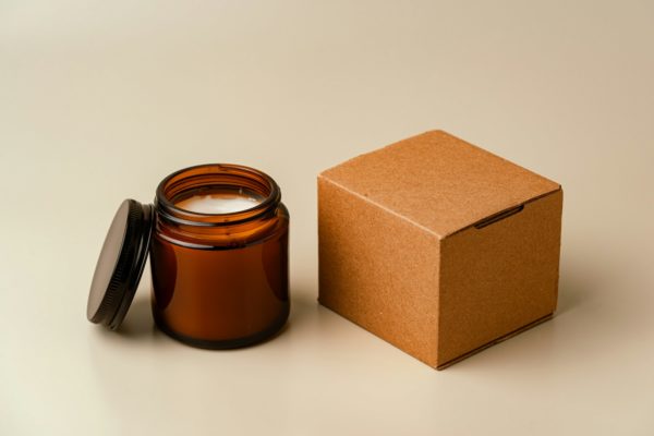 Glass Candle Jar and Cardboard Box on Beige Background